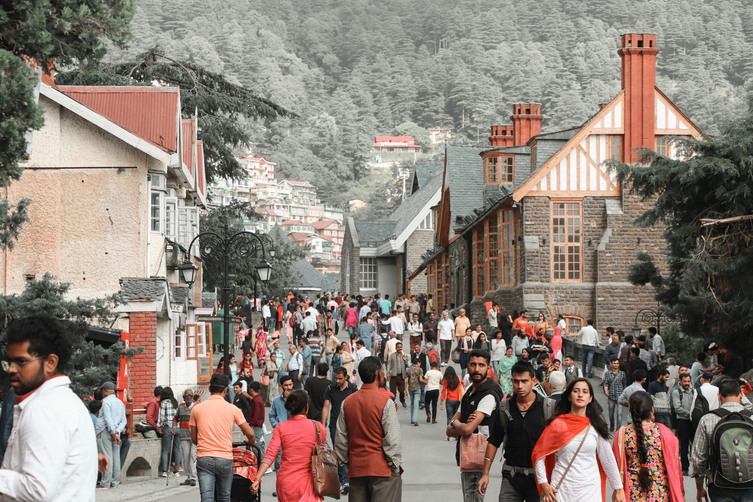 Lively crowd on a street in Shimla, India, surrounded by historic architecture and scenic hills.